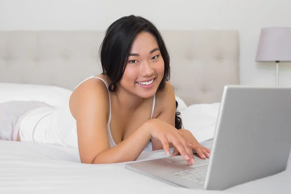 Mujer feliz acostada en la cama usando portátil —  Fotos de Stock