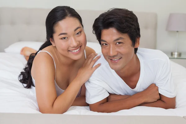 Happy couple lying on bed together — Stock Photo, Image