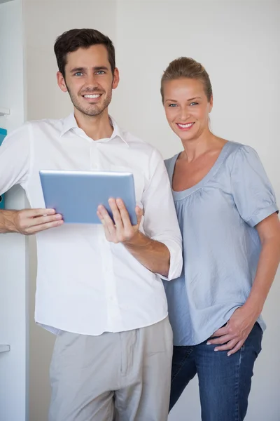 Casual business team smiling at camera man holding tablet — Stock Photo, Image