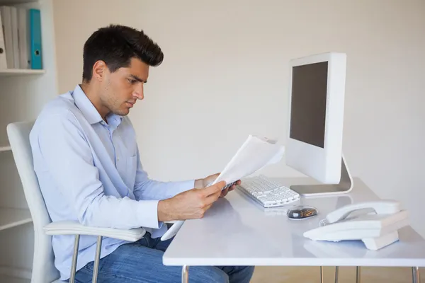 Dorywczo biznesmen czytanie dokumentu przy jego biurku — Zdjęcie stockowe