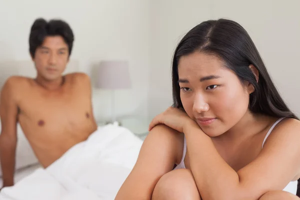 Freund schaut Freundin an, die auf Bett sitzt — Stockfoto