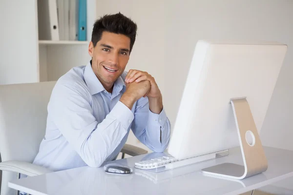 Hombre de negocios casual sonriendo a la cámara en su escritorio —  Fotos de Stock