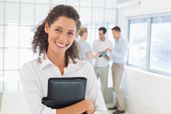 Casual businesswoman smiling at camera holding diary — Stock Photo, Image