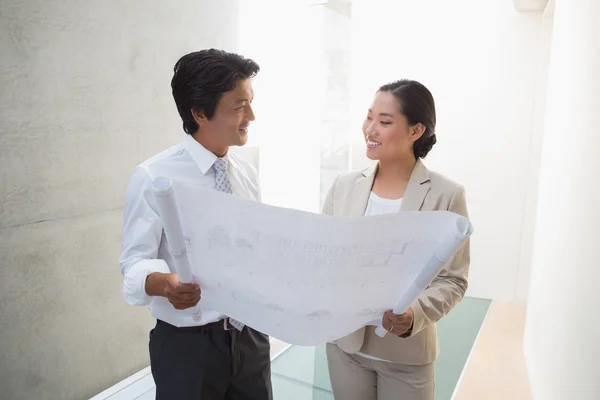 Estate agent looking at blueprint with potential buyer — Stock Photo, Image