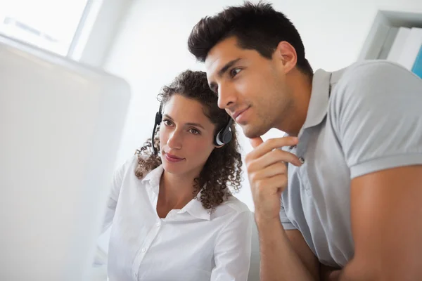 Casual businessman looking at colleagues computer — Stock Photo, Image