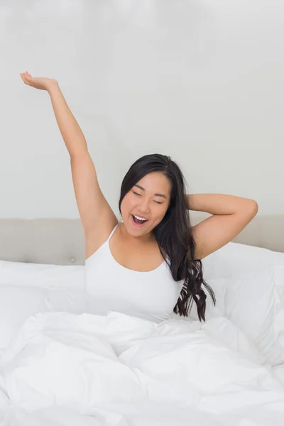 Mujer sonriente estirándose en la cama por la mañana —  Fotos de Stock