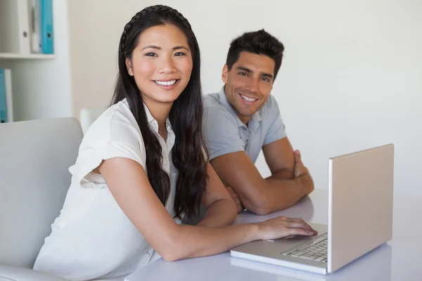 Casual business team using laptop together at desk — Stock Photo, Image