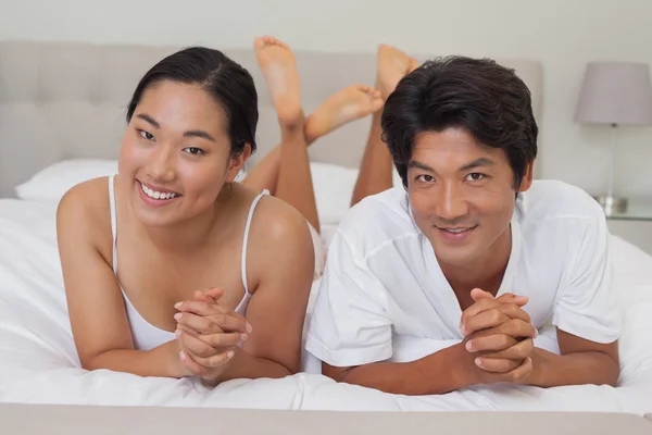 Casal feliz deitado na cama juntos — Fotografia de Stock