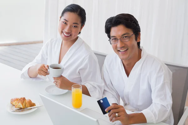 Couple in bathrobes shopping online in the morning — Stock Photo, Image