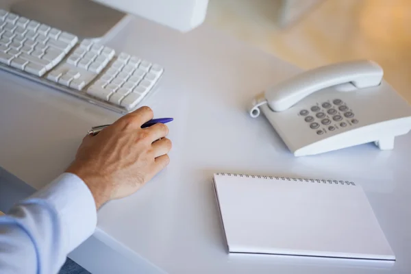 Hombre de negocios casual en el escritorio con bloc de notas y teléfono — Foto de Stock