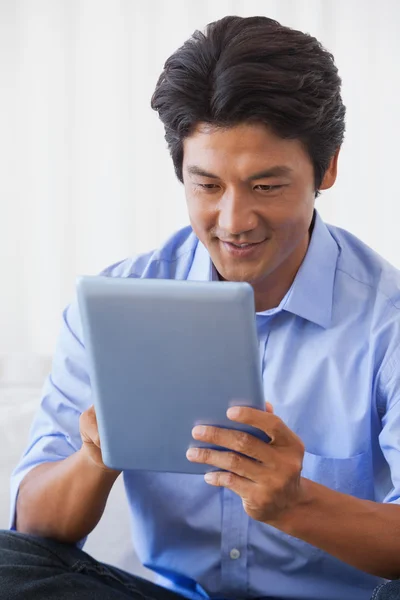 Happy man sitting on couch using tablet — Stock Photo, Image