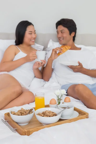 침대에서 아침을 먹고 있는 행복 한 부부 — 스톡 사진