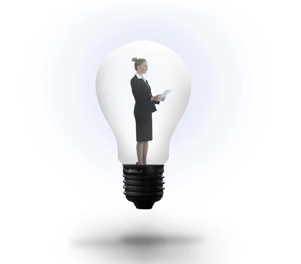 Businesswoman holding tablet in light bulb — Stock Photo, Image