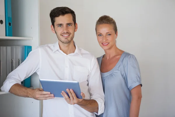 Equipo de negocios casual sonriendo al hombre de la cámara sosteniendo la tableta —  Fotos de Stock