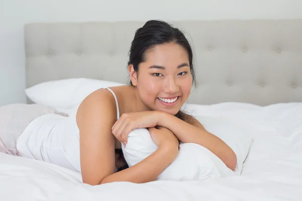 Smiling asian woman lying on bed — Stock Photo, Image