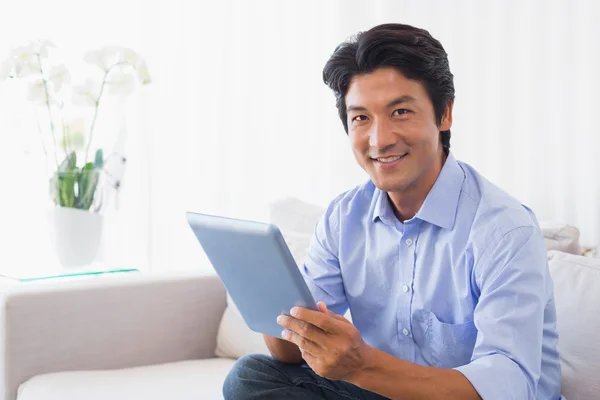 Glücklicher Mann sitzt mit Tablet-PC auf Couch — Stockfoto