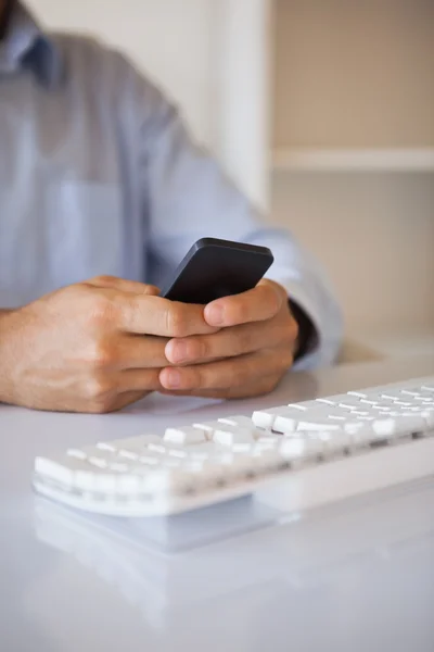 Biznesmen SMS na telefon na biurko — Zdjęcie stockowe