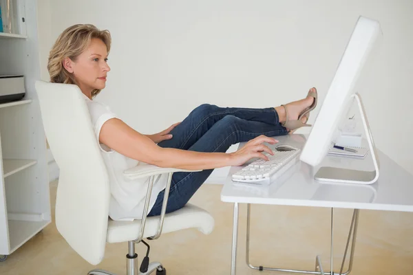 Mujer de negocios casual trabajando con los pies en el escritorio —  Fotos de Stock