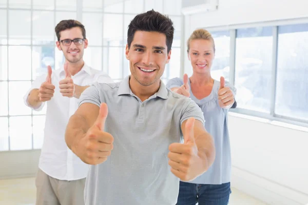 Casual zakelijke team glimlachen op camera met duimen omhoog — Stockfoto