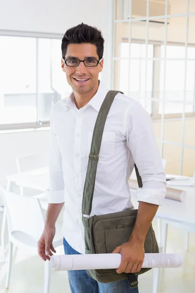 Casual handsome architect smiling at camera holding blueprint — Stock Photo, Image