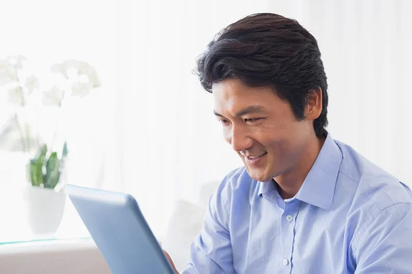 Szczęśliwy człowiek siedzi na kanapie przy użyciu komputera typu tablet — Zdjęcie stockowe