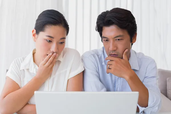 Casal preocupado usando laptop juntos — Fotografia de Stock