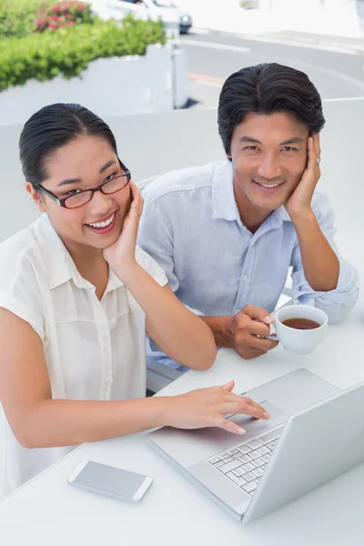 Smiling couple having breakfast together using laptop — Stock Photo, Image