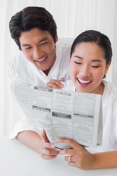 Couple in bathrobes reading newspaper together in the morning — Stock Photo, Image