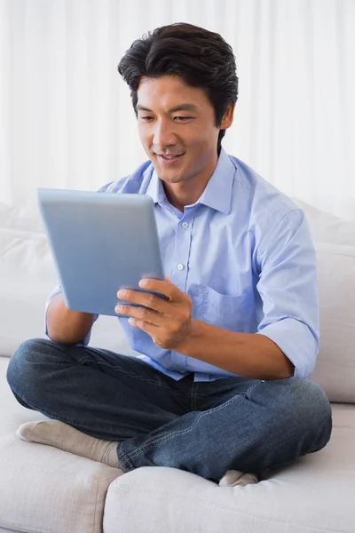 Szczęśliwy człowiek siedzi na kanapie przy użyciu komputera typu tablet — Zdjęcie stockowe