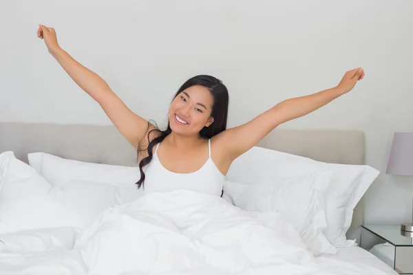 Mulher sorridente que se estende na cama pela manhã — Fotografia de Stock