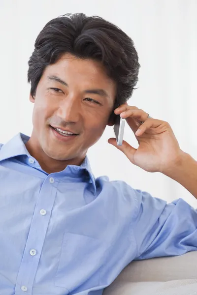 Glücklicher Mann, der auf Couch am Telefon sitzt — Stockfoto