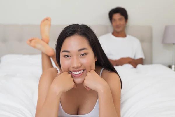 Donna sdraiata sul letto sorridente alla macchina fotografica — Foto Stock