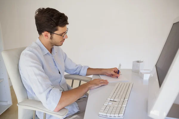 Casual zakenman die aantekeningen maakt op zijn Bureau — Stockfoto