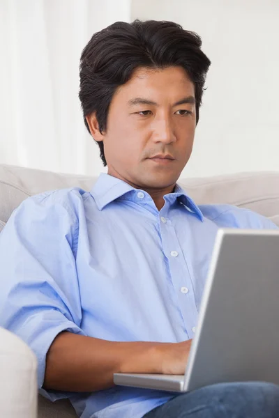 Allvarlig man sitter på soffan med laptop — Stockfoto