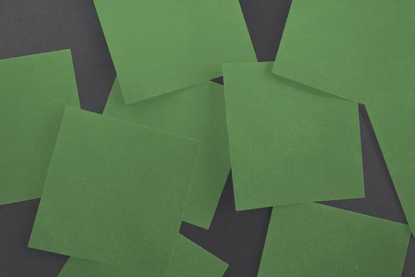 Grünes Papier über Schwarz gestreut — Stockfoto