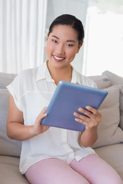 Mujer sonriente sentada en el sofá usando tableta pc — Foto de Stock