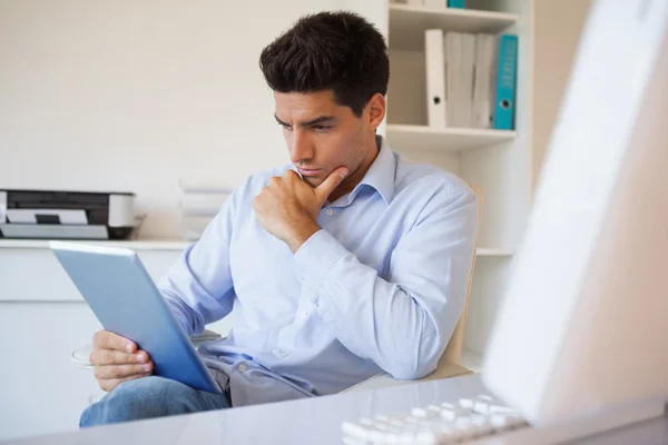 Hombre de negocios casual usando su tableta en su escritorio — Foto de Stock