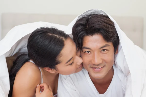 Happy couple lying on bed together under the duvet — Stock Photo, Image