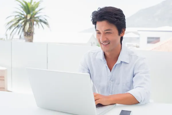 Улыбающийся человек использует свой ноутбук — стоковое фото