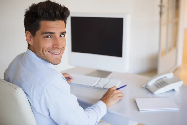 Hombre de negocios casual en el escritorio sonriendo a la cámara — Foto de Stock