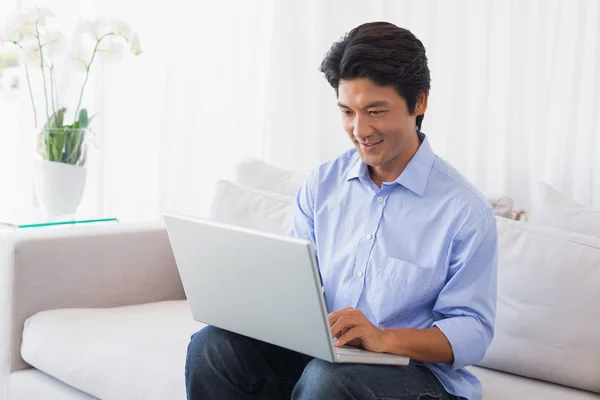 Glücklicher Mann sitzt mit Laptop auf Couch — Stockfoto