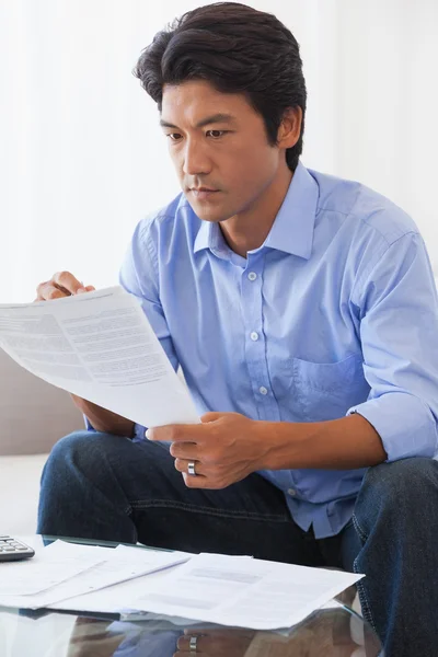 Seriöser Mann sitzt auf Couch und bezahlt seine Rechnungen — Stockfoto