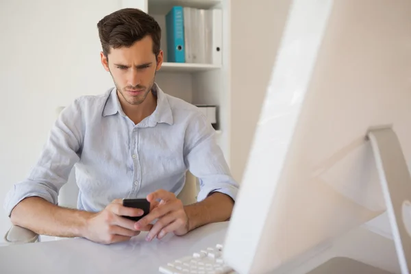 Casual zakenman sturen van een tekst op zijn Bureau Rechtenvrije Stockafbeeldingen