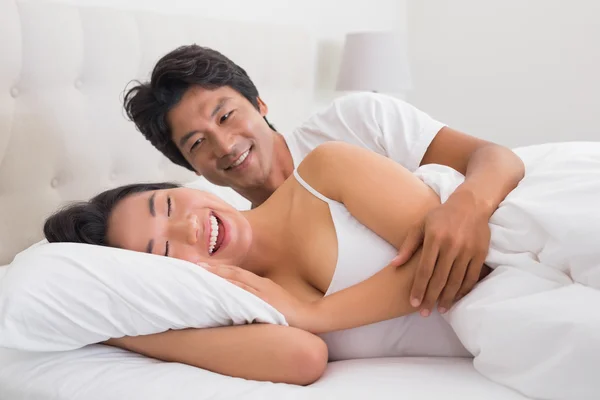 Sorridente coppia sdraiata a letto — Foto Stock