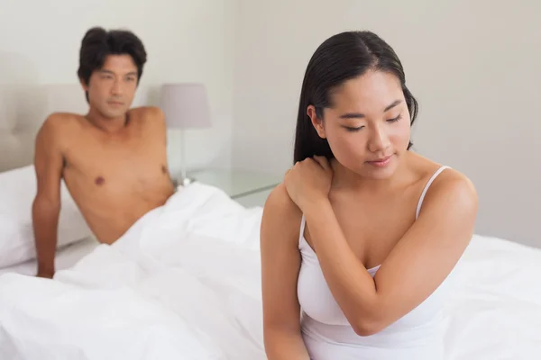 Boyfriend looking at girlfriend sitting on end of bed — Stock Photo, Image