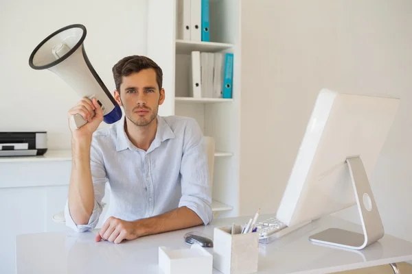 Casual homem de negócios sentado na mesa com megafone — Fotografia de Stock