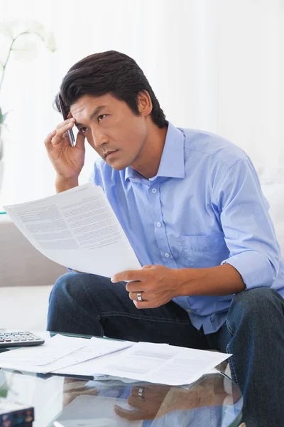 Seriöser Mann sitzt auf Couch und bezahlt seine Rechnungen — Stockfoto