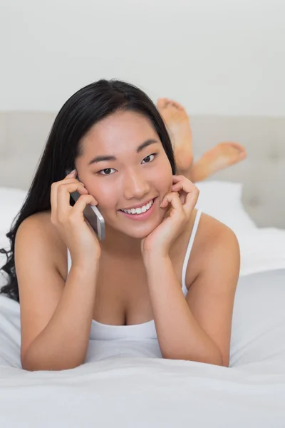 Gelukkige vrouw liggen op bed op een telefoongesprek — Stockfoto