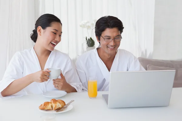 Happy couple using laptop over breakfast — Stock Photo, Image