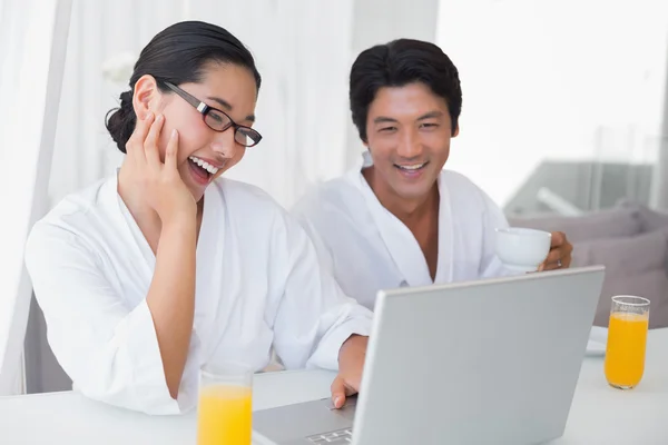 Paar in Bademänteln verbringt den Morgen zusammen mit Laptop — Stockfoto